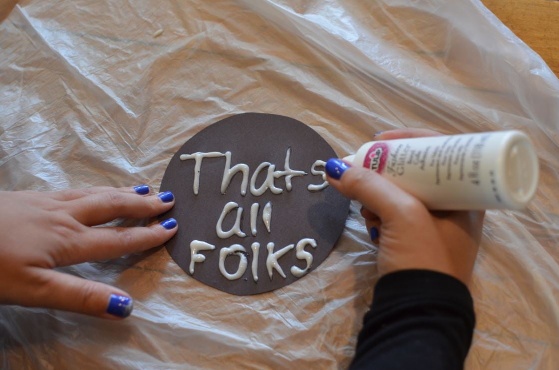 Writing a message on a sign with glitter glue