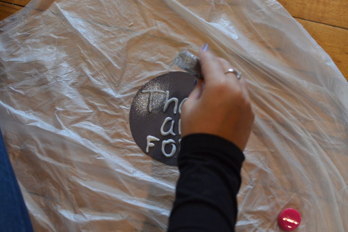 Applying glitter to a sign while protecting the surface underneath